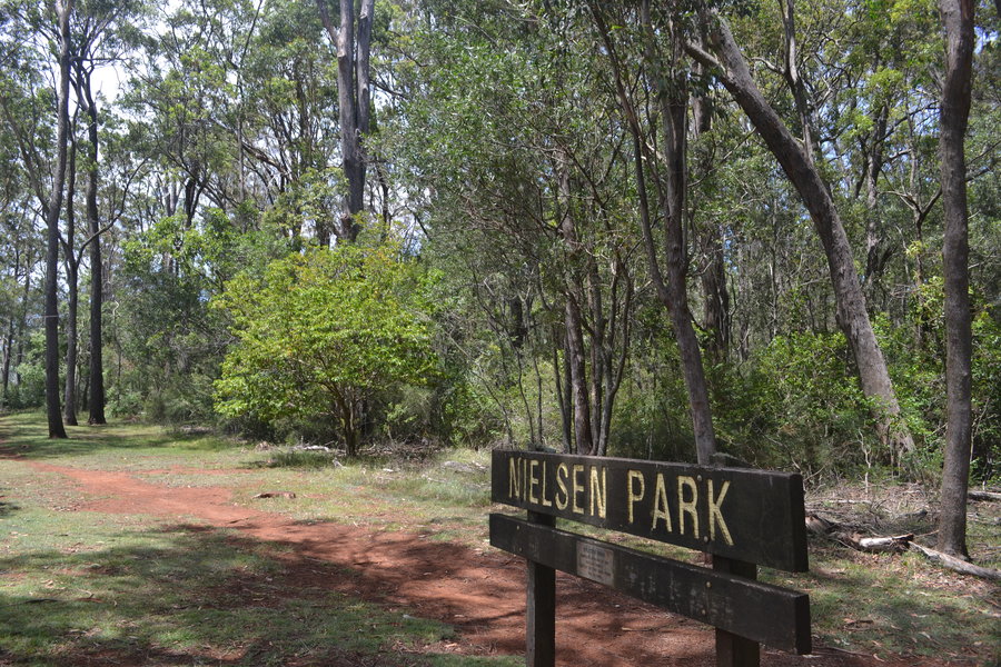 Nielsen park entry sign leading to dirt path surrounded by bushland.