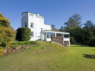 Recent photo of Geeumbi house. A tall white multi-level home surrounded by lush green grass.