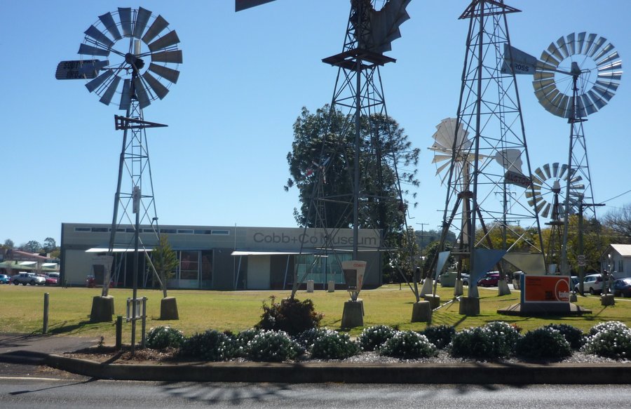 Recent photo of the Cobb and Co museum, taken from the corner of Lindsay and Campbell Streets. Six southern cross windmills in the foreground of the photo.
