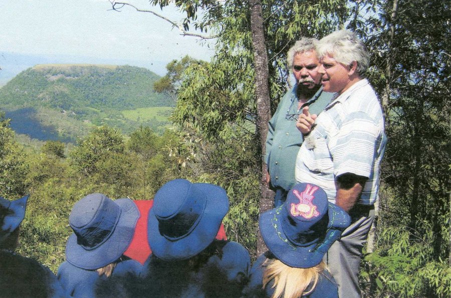 Unveiling the multuggerah plaque in Duggan Park. Two men stand with a group of primary school children looking out towards Tabletop mountain.