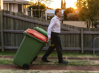 Man taking rubbish bins to the curb
