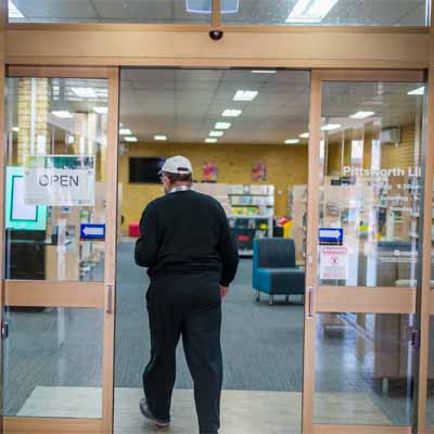 Man walking through the auto doors entering Pittsworth Library