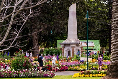 Queens Park Botanic Gardens during Carnival of Flowers. Colourful floral garden beds surrounding the memorial statue centrepiece.