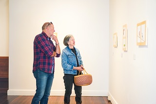Two people looking at artwork on the wall.