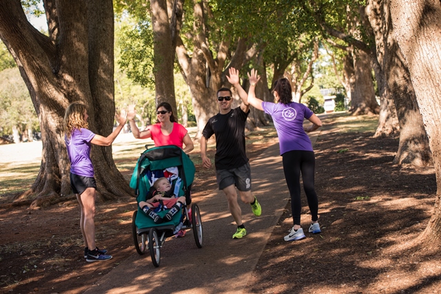 parkrun family with child in pram high fiving two parkun volunteers
