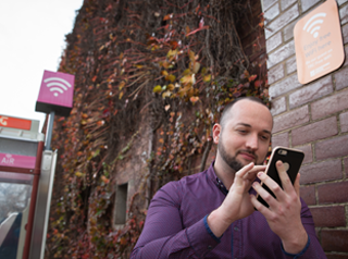 Man using mobile close to free wi-fi sign